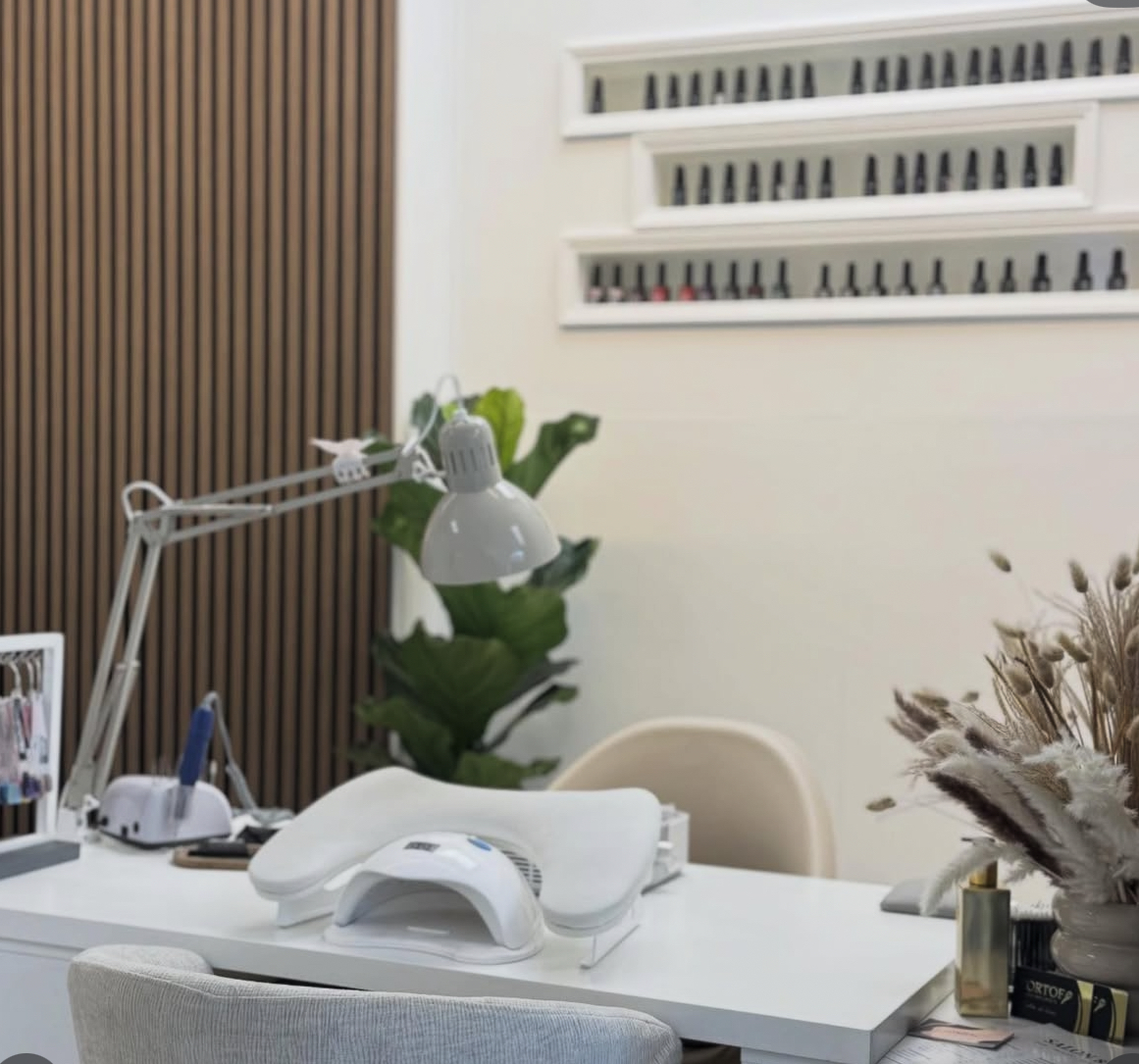 De nageltafel in Salon8 met lamp, lakjes op verlichte planken en een wand van houten lamellen