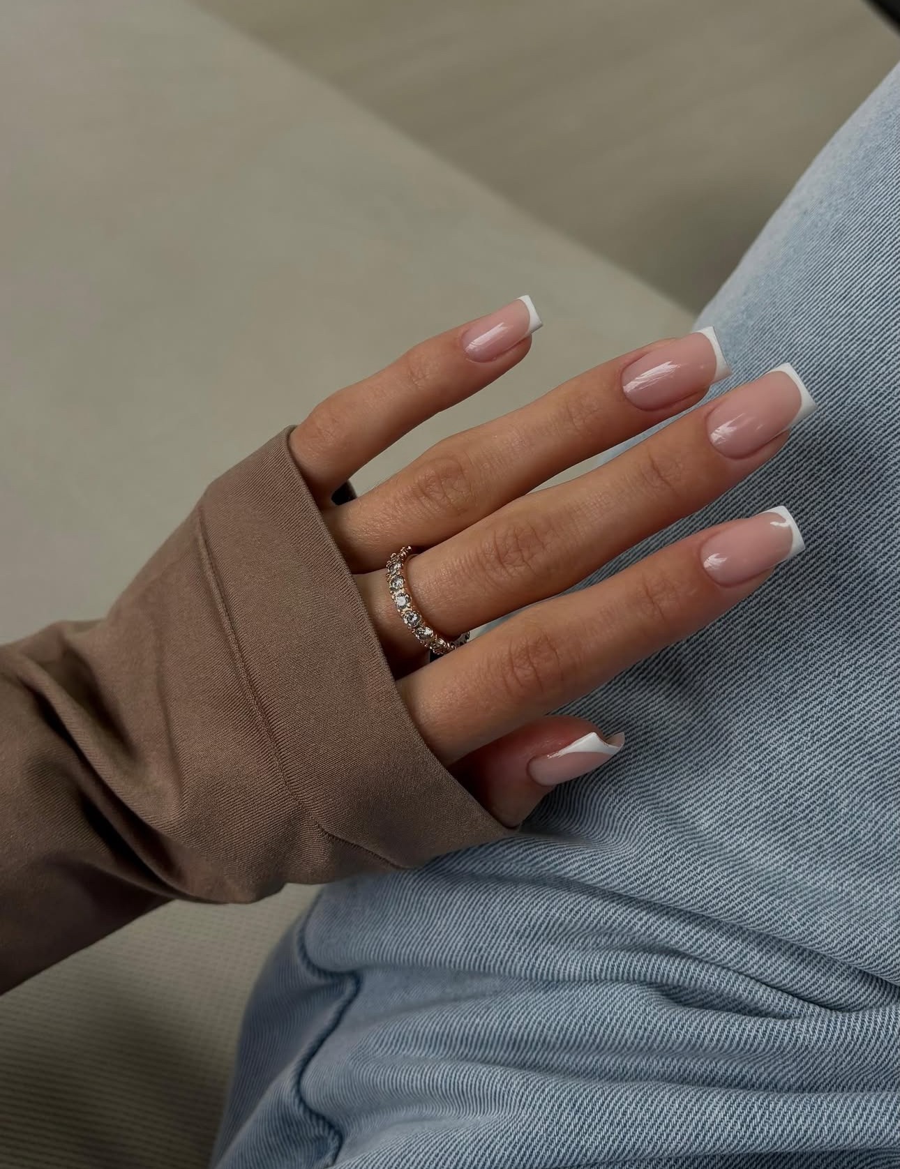 Een hand met verzorgde nagels in een zachte French manicure